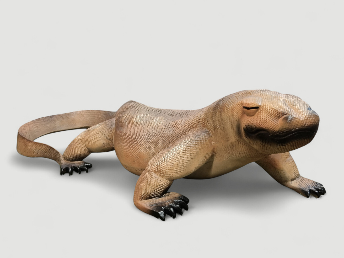 Komodowaran-Statue aus Steinguss. Dekorative Gartenfigur eines liegenden Warans, detailreich gestaltet.