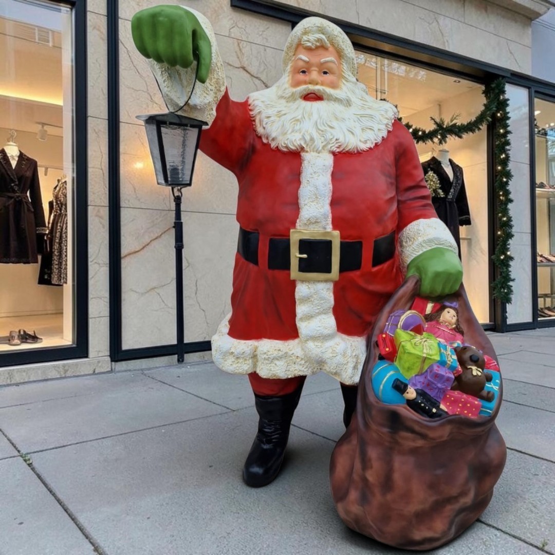 Lebensgroßer stehender Weihnachtsmann mit Laterne und Sack voller Geschenke.