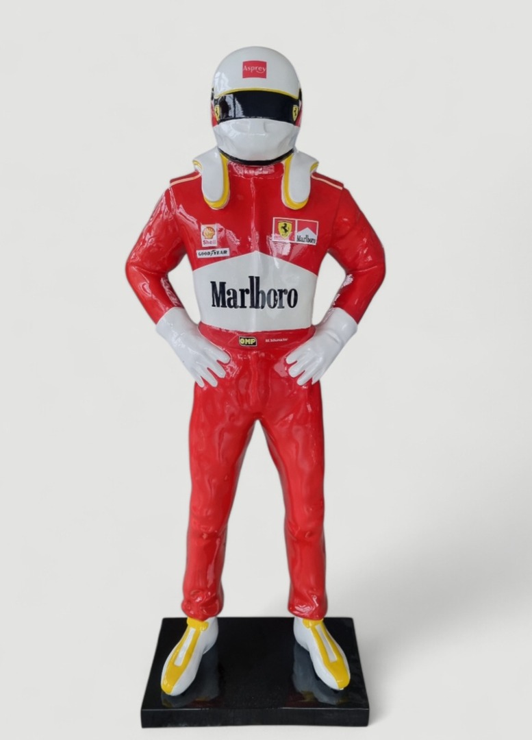 Formel-1-Fahrer Statue: Roter Rennanzug, Helm, auf schwarzem Sockel.