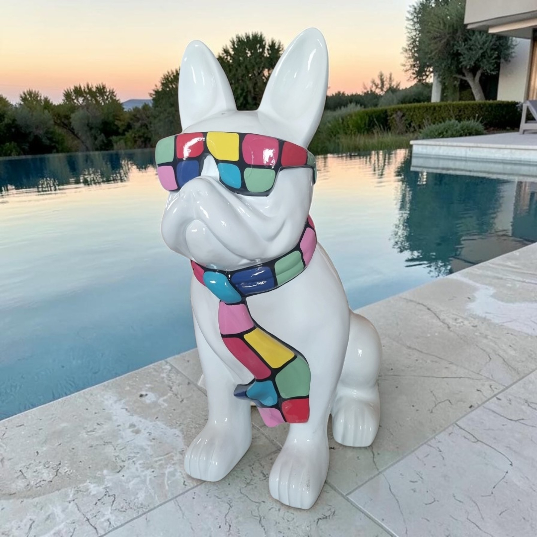 Weiße Französische Bulldogge Gartenfigur mit bunter Brille und Schal, sitzend.