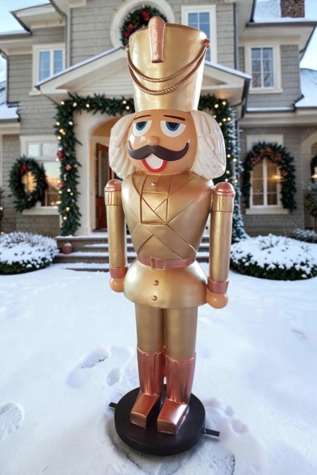 Lebensgroßer Nussknacker XXL in goldener Uniform vor einem winterlichen Haus mit Schnee.