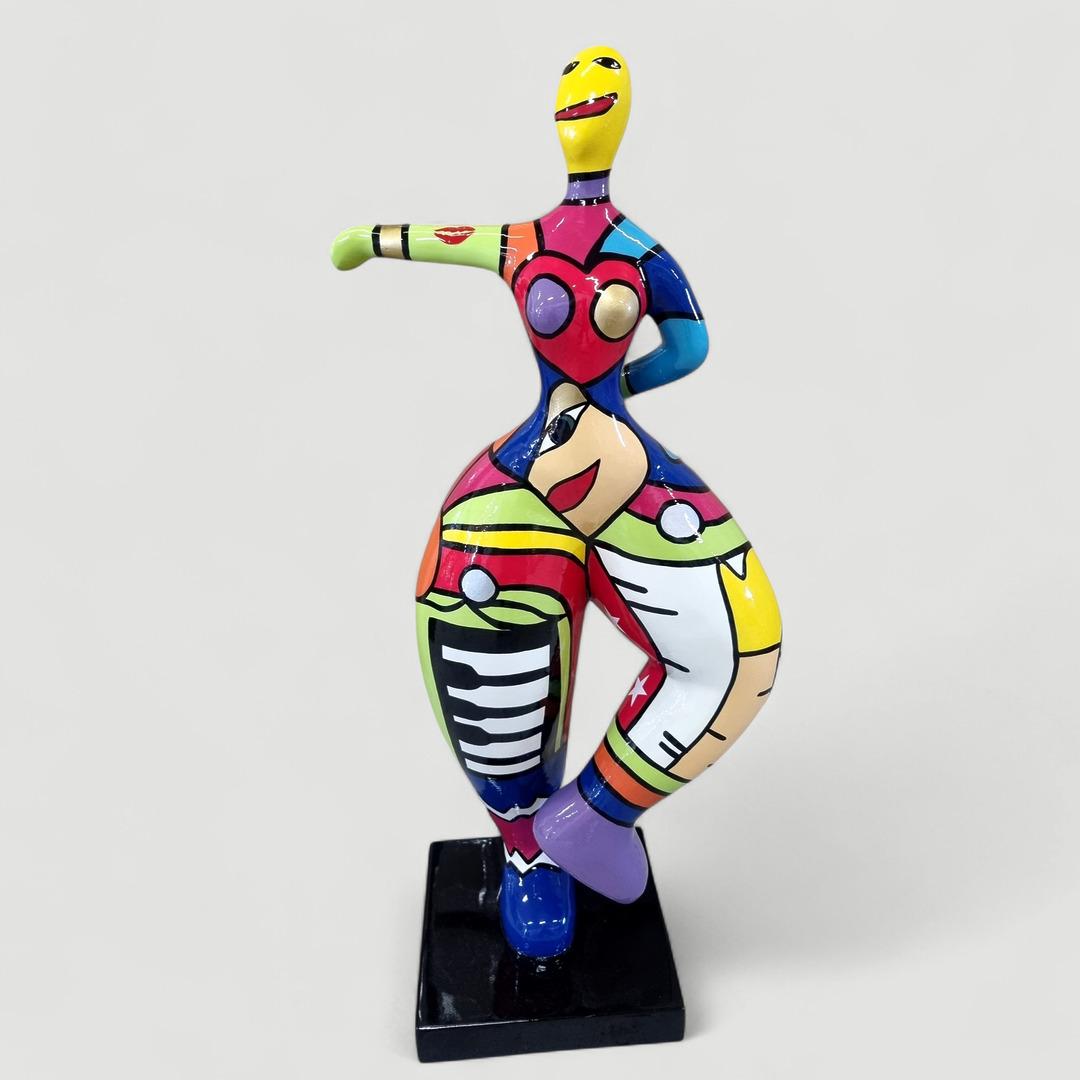 Bunte Statue einer tanzenden Frau auf schwarzem Sockel.