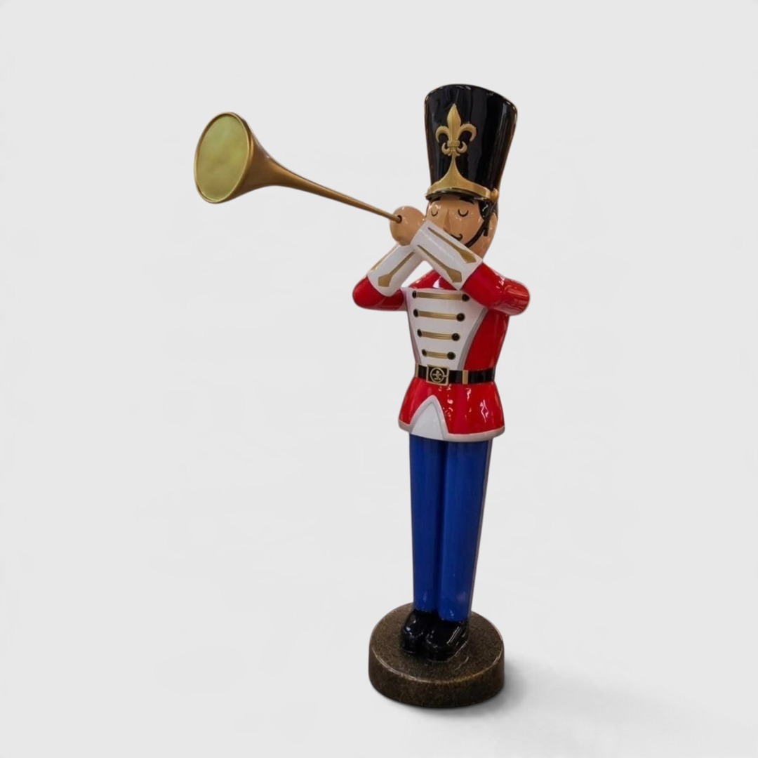 Bunte Spielzeugsoldatenfigur mit Trompete, rot-weißer Uniform und blauen Hosen.
